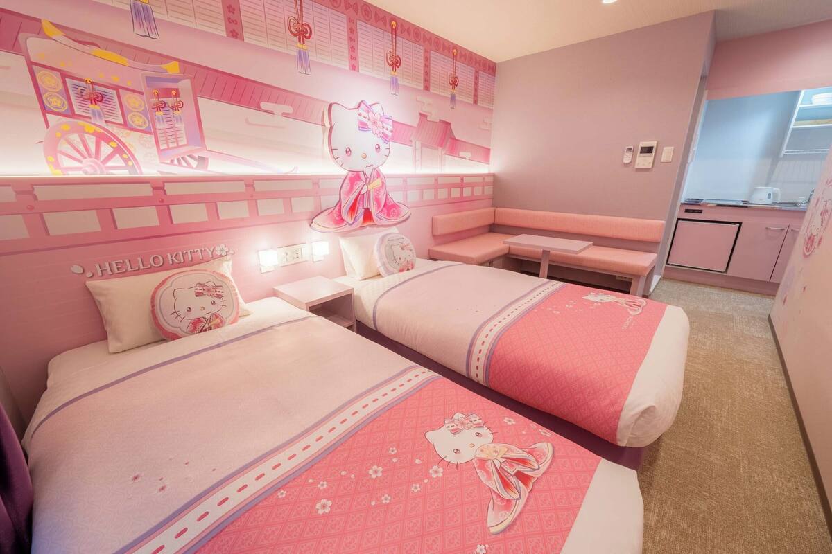 Ein Hotelzimmer in Rosa mit zwei Betten, einer Sitzbank und einer Küchenzeile.