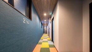 Een hal met een geruit vloerpatroon, een bordje met het nummer '2' aan de muur en een plafond met inbouwverlichting.
