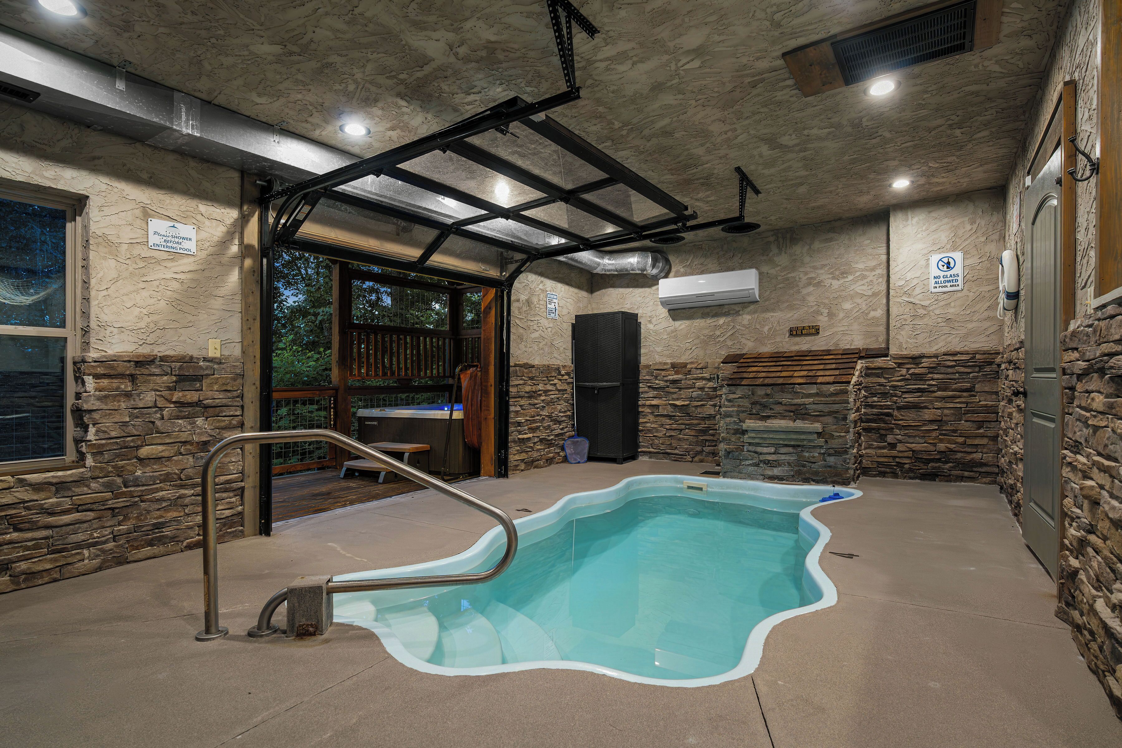 A pool area with a built-in hot tub, stone walls, and a glass door leading outside.