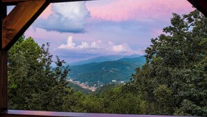 A view from a wooden balcony overlooking a valley with mountains in the distance and a pink sky. - Free Attractions Pvt Pool, Mtn and City views. View fireworks from Hot tub! (Gatlinburg)