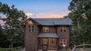A two-story wooden cabin with a stone entrance, surrounded by a wooden fence and a stone pathway. - Free Attractions Pvt Pool, Mtn and City views. View fireworks from Hot tub! (Gatlinburg)