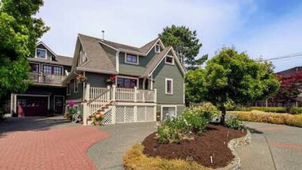 A two-story house with a front porch, a garage, and a landscaped front yard. - Character Stay across Swan Lake Nature Sanctuary (Victoria)