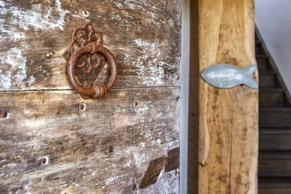 A rustic wooden door with a metal ring handle and a 'Bienvenue' sign.