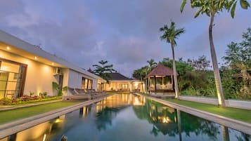 A modern resort with a swimming pool, lounge chairs, and a gazebo.
