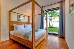 A four-poster bed with a wooden frame, white bedding, and a checkered throw.