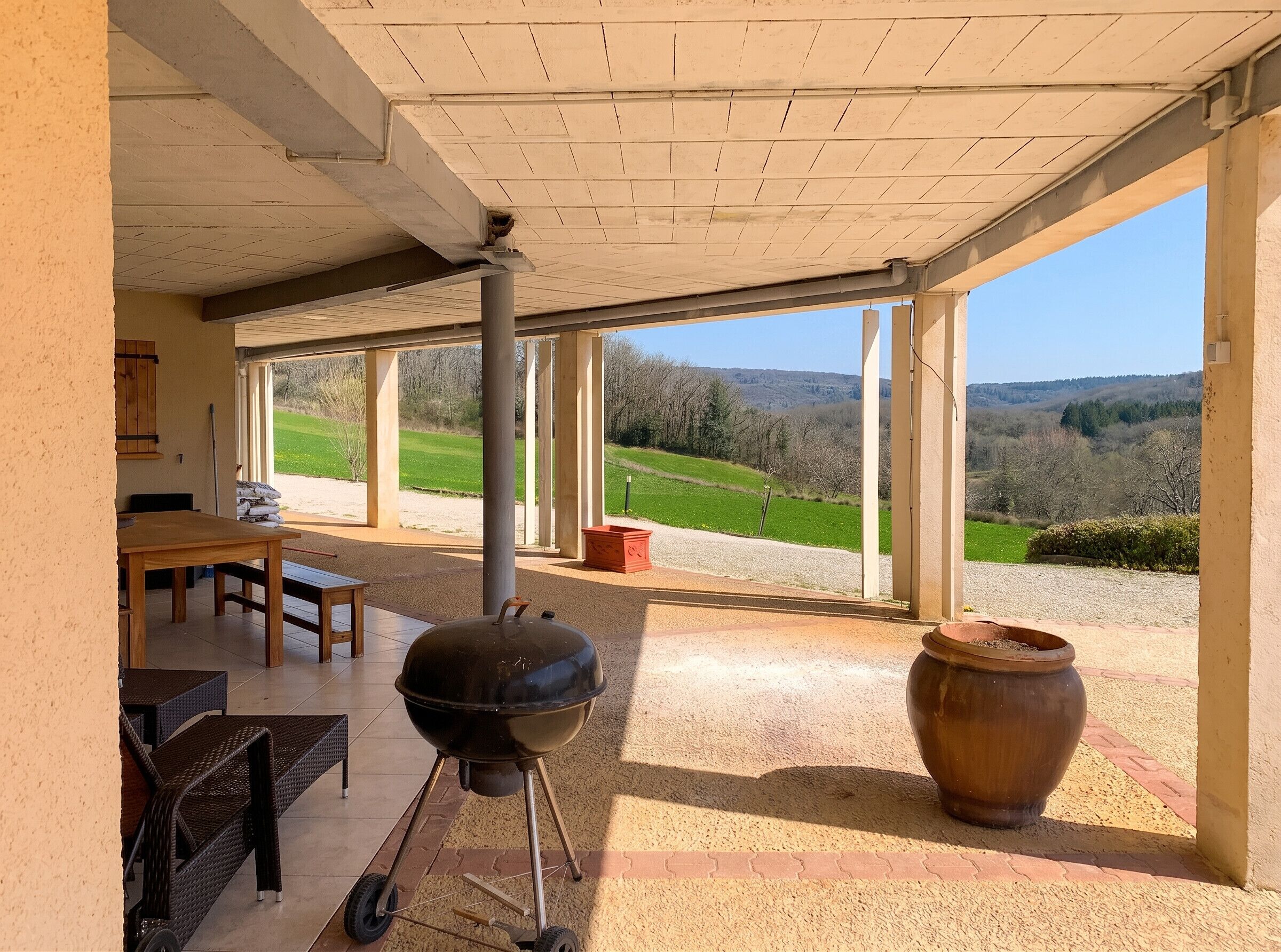 An outdoor patio with a grill, seating, and a view of the countryside.