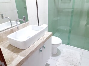 Bathroom features a large sink, toilet, and green glass panels.