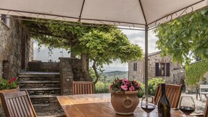 A rustic outdoor dining area with a wooden table, chairs, and a large vase of flowers. - Villa Dipendenza, Historic Holding with  wonderful swimming pool (murlo - siena, tuscany)