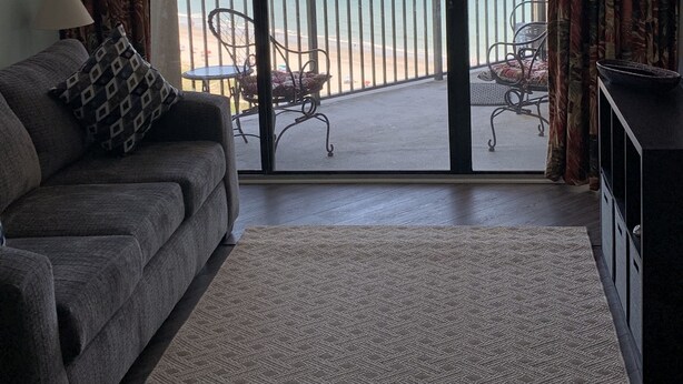 Ein Wohnzimmer mit einer Couch, einem Couchtisch und Blick auf den Strand durch eine Schiebetür.