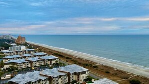 Ein Küstenhotel mit mehreren Gebäuden, einem Strand und Blick auf den Ozean.