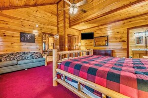 A wooden cabin interior with a bed, sofa, and a ceiling fan. - Pools Rush Inn (Cosby)