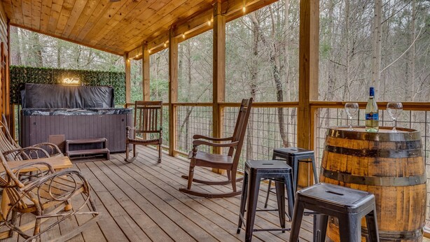 A wooden deck with a hot tub, rocking chairs, and a bar area with a barrel. - Heated Pool, Movie Room, Sleeps 30, Dogs Welcome (Cosby)
