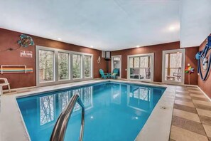 En inomhuspool med väggar av genomskinligt glas, en skylt som förbjuder dykning och en poolstege.