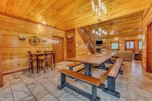 A wooden interior with a dining area, benches, a staircase, and a fireplace. - Pools Rush Inn (Cosby)