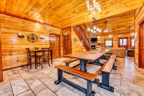 A wooden interior with a dining area, benches, a fireplace, and a staircase. - Mountain Retreat • Sleeps29 • Pool • HotTub • Dogs (Cosby)