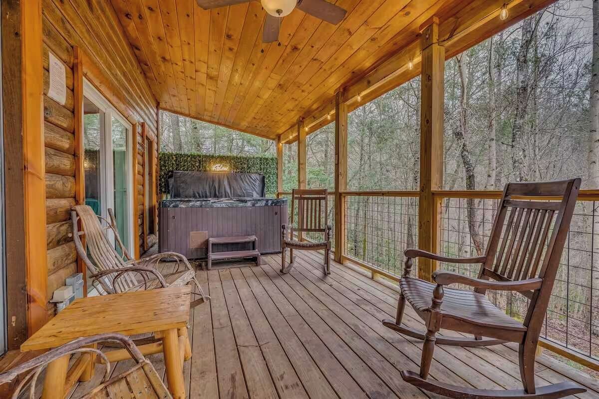 A wooden deck with a hot tub, rocking chairs, and a table.