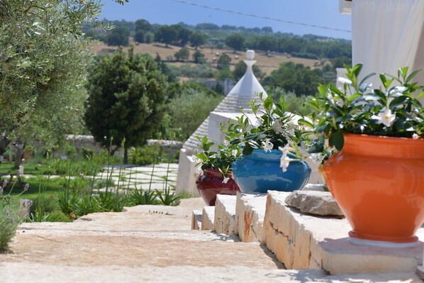 A stone pathway leading to a terrace with potted plants and a view of a rural landscape. - Luxury Holiday in Valle D'Itria (Locorotondo)
