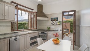 A modern kitchen with a dishwasher, oven, and a dining area with a table and chairs.