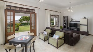 A living room with a sofa, chairs, a TV, and a dining table.