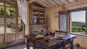Un comedor rústico con una mesa de madera, sillas y vistas al campo.