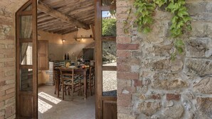 Una cocina rústica con una mesa de madera, sillas y una pared de ladrillo.