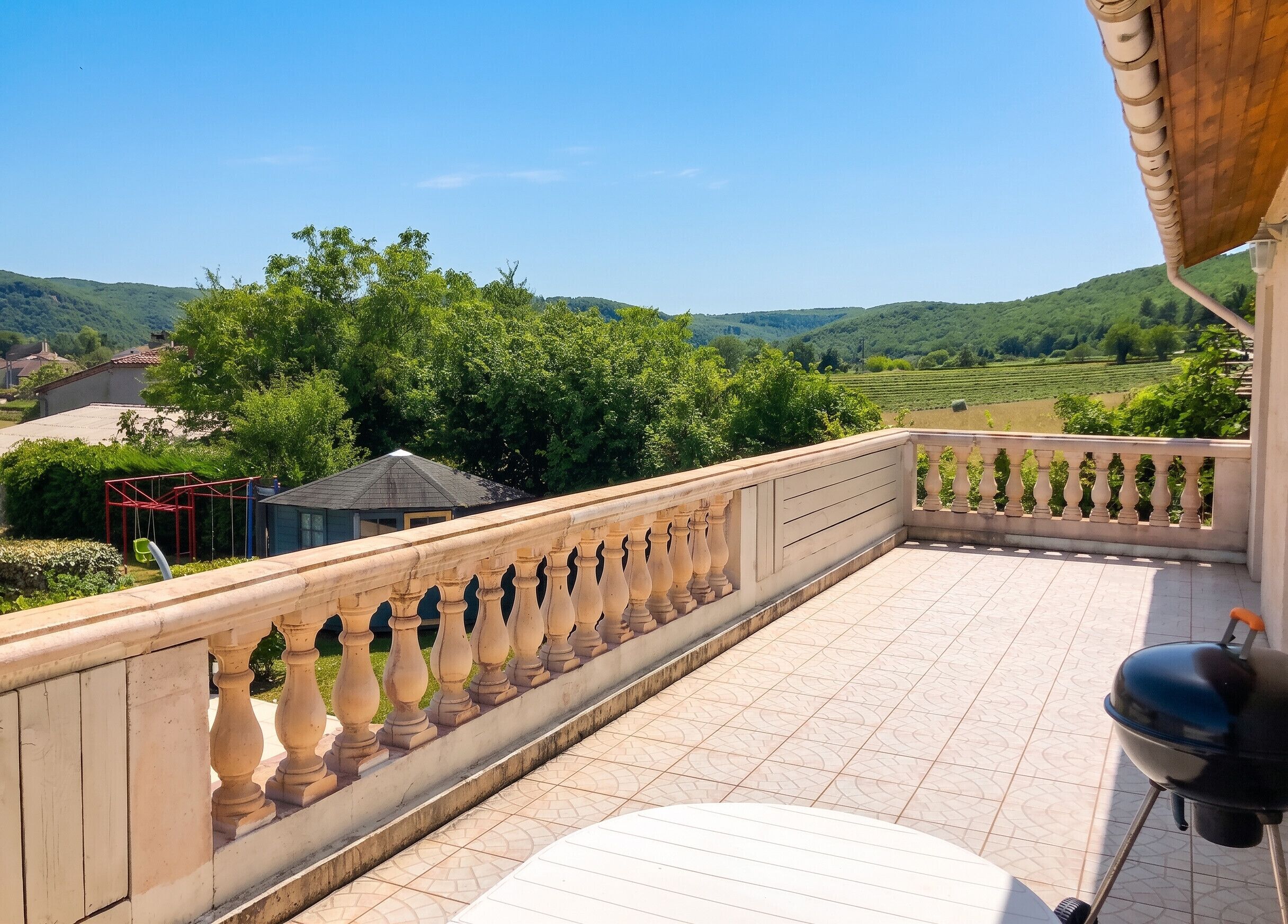 Een balkon met uitzicht op groene heuvels en een heldere lucht.