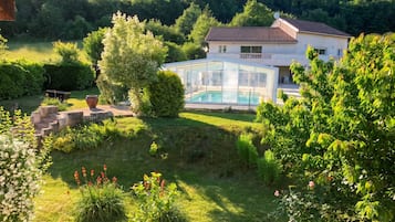 Ein Haus mit Schwimmbad, umgeben von üppiger Vegetation und einer hügeligen Landschaft.