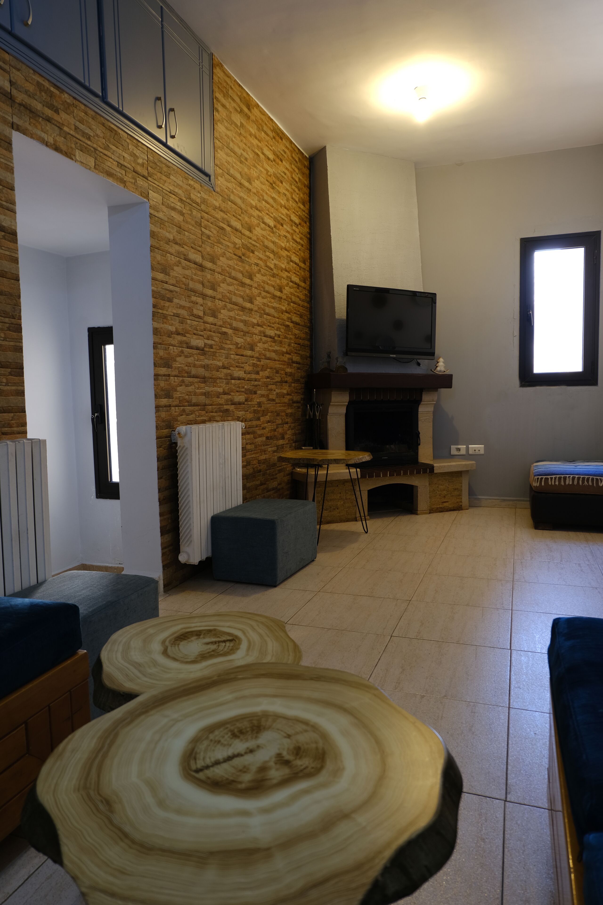 A living room with a fireplace, a television, and a stone wall.