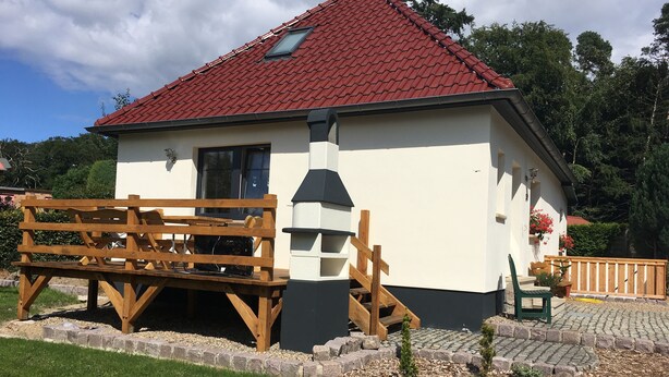 Um pequeno edifício térreo com telhado de telhas vermelhas e fachada branca.