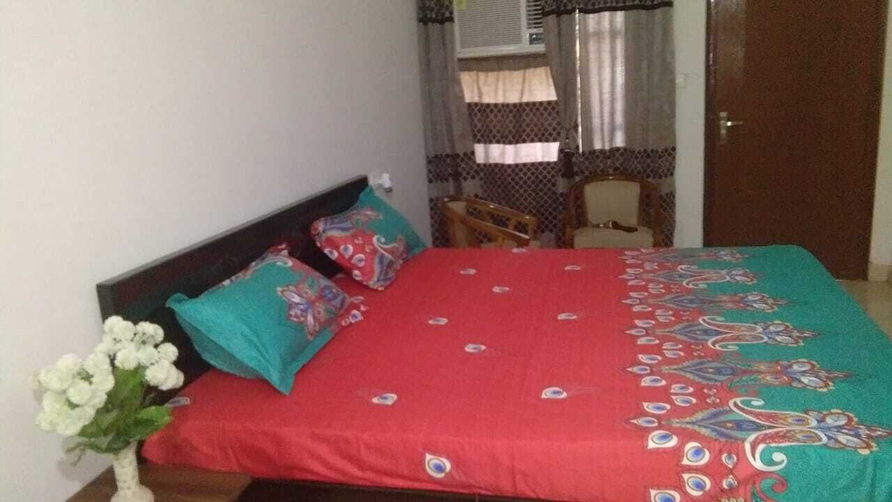 A bedroom with a bed, a chair, and a window with curtains.