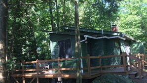 A rustic cabin with a wooden deck and a small porch. - Honeymooners/Getaway Studio on Lovely Lake Iroquois near Burlington (Hinesburg)