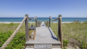 A wooden boardwalk leading to the beach with ropes on either side and a sign that reads "HEAD TO THE BEACH." - *Oceanfront Beach Home* (Sandwich)