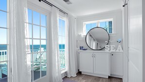 A room with large windows, a round mirror, and a view of the sea. - *Oceanfront Beach Home* (Sandwich)