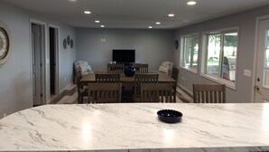 A dining area with a marble table, wooden chairs, a large vase, and a television on the wall. - Sunken Lake Cottage, w/ 2 Kayaks, Paddle Boat and Canoe (Posen)