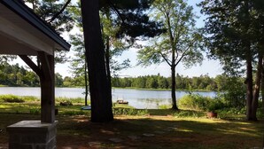 A lakeside property with a covered patio, stone steps leading to a dock, and a view of the lake. - Sunken Lake Cottage, w/ 2 Kayaks, Paddle Boat and Canoe (Posen)