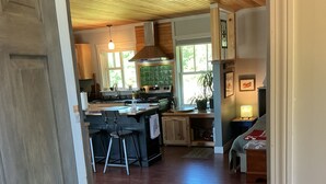 A kitchen with a central island, wooden flooring, and a view of the living area. - 24 - Funky and charming, 'small house' in West Tremont (Tremont)