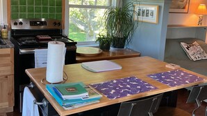 A kitchen with a stove, a window, a plant, and a bar area with chairs. - 24 - Funky and charming, 'small house' in West Tremont (Tremont)