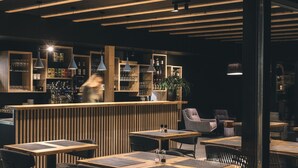 A modern bar area with wooden furniture and pendant lighting. - Hotel Majer'ca (Bohinj)