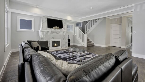 A spacious living room with a fireplace, a large leather sofa, and a staircase leading to an upper level. - LOCATION,PRACTICALITY AND COMFORT MEET! BEACH BLOCK! BRING YOUR EXTENDED FAMILY! (Atlantic City)