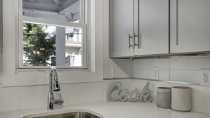 A kitchen with white cabinets, a stainless steel sink, a window, and a 'Cook' sign. - LOCATION,PRACTICALITY AND COMFORT MEET! BEACH BLOCK! BRING YOUR EXTENDED FAMILY! (Atlantic City)