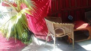 A room with a red table, a wicker chair, a wall clock, and a potted plant. - Orkide Apart Hotel (Ula)