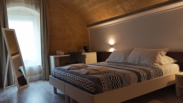 A bedroom with a bed, bedside tables, a desk, and a chair. - In & Out Matera (Matera)