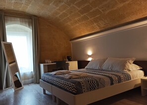 A bedroom with a bed, bedside tables, a desk, and a chair. - In & Out Matera (Matera)