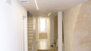 A hallway with a tiled floor, white walls, and a staircase leading to another room. - In & Out Matera (Matera)