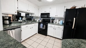 A kitchen with white cabinets, a black refrigerator, a stove, and a microwave. - Sugartop Resort 6th-Floor Corner Condo: Breathtaking Mountain Views - 2BR (Sugar Mountain)