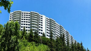 A multi-story hotel with balconies, surrounded by greenery. - Sugartop Resort 6th-Floor Corner Condo: Breathtaking Mountain Views - 2BR (Sugar Mountain)