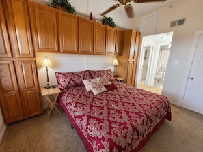 A bedroom with a bed, wooden cabinets, two bedside lamps, and a ceiling fan.