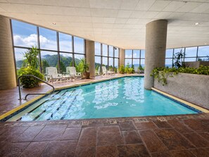 An indoor swimming pool with clear views of mountains through large windows.
