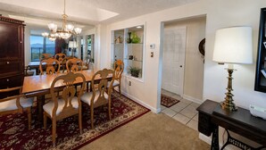 A dining area with a wooden table and chairs, a chandelier, and a view through an open door. - Sugartop Resort 6th-Floor Corner Condo: Breathtaking Mountain Views - 2BR (Sugar Mountain)