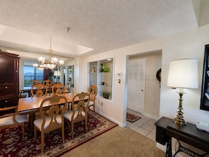 A dining area with a wooden table and chairs, a chandelier, and a view through an open door. - Sugartop Resort 6th-Floor Corner Condo: Breathtaking Mountain Views - 2BR (Sugar Mountain)